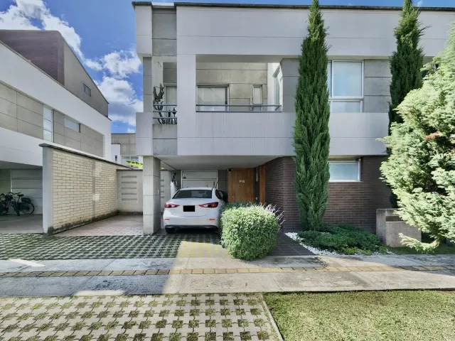 This stunning white house features two parking spaces (one covered and one uncovered) and a charming front garden with a pine tree. Perfect for those looking for a serene and inviting home in a gated community.